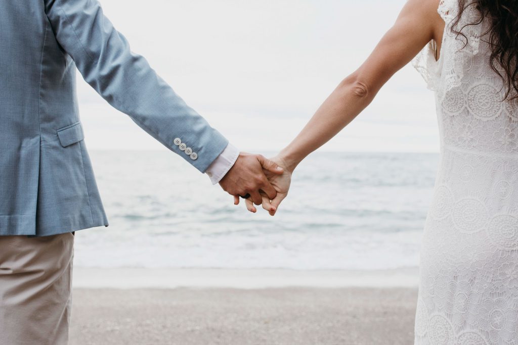 Close-up of a couple holding hands during their beach elopement, symbolizing love and commitment
